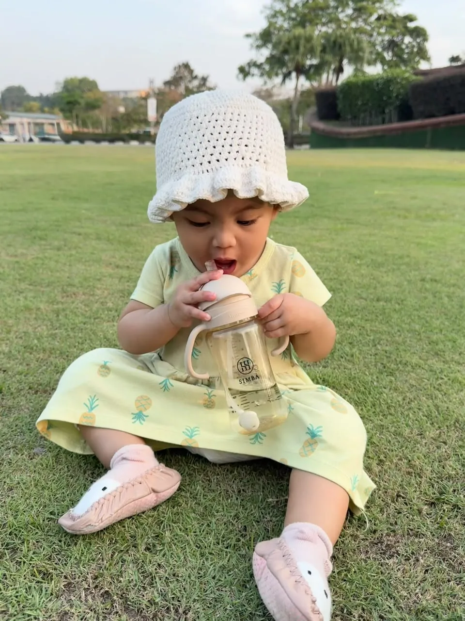 Bayi memakai bonnet putih di padang