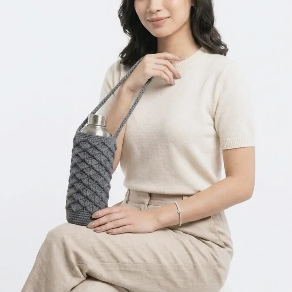 Model duduk memegang sling botol kelabu